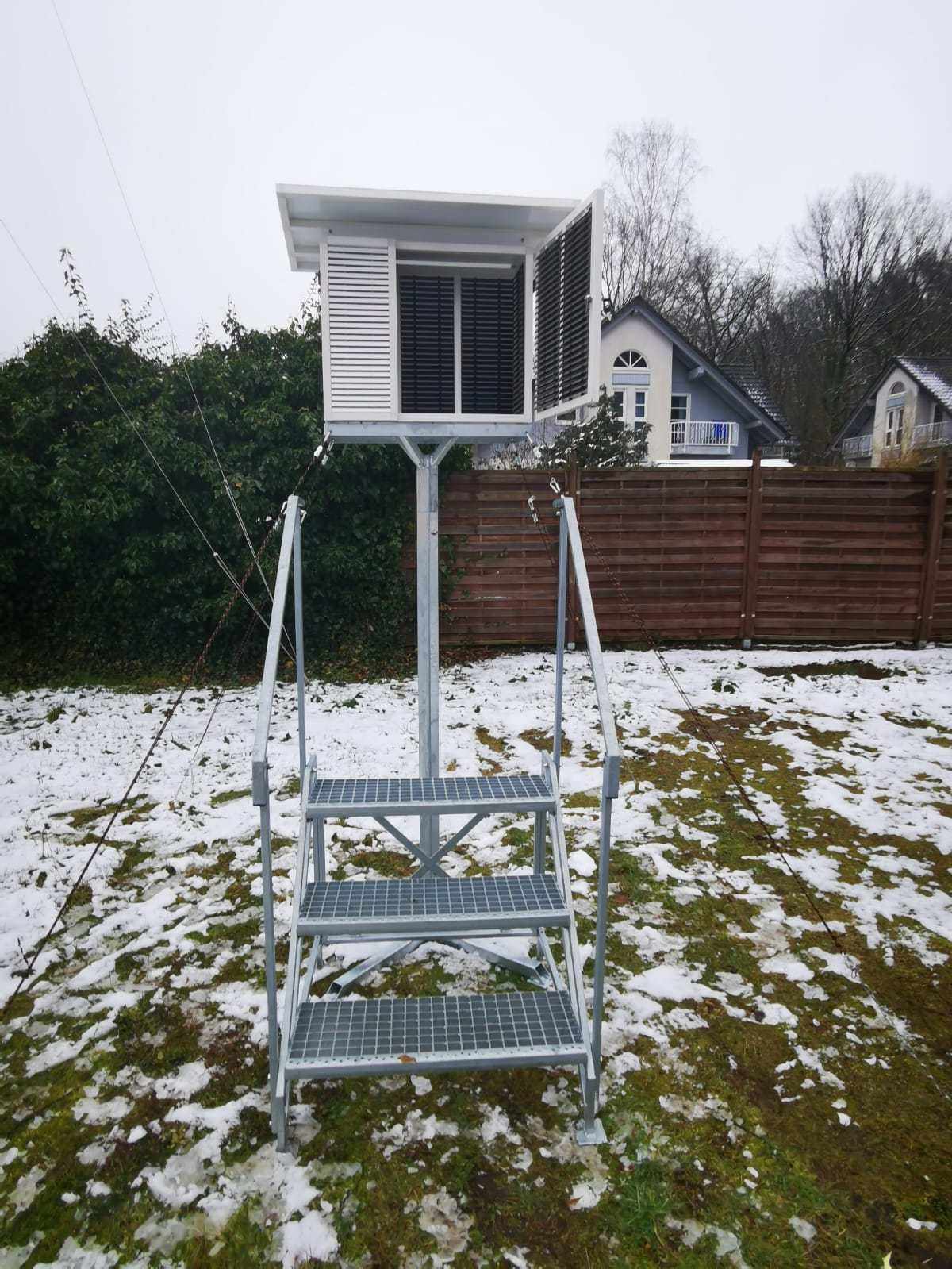 Wetterhütte in Modulbauweise mit Hygrometer, doppelter Breite, außen RAL9010, auf Metallgestell im Garten.