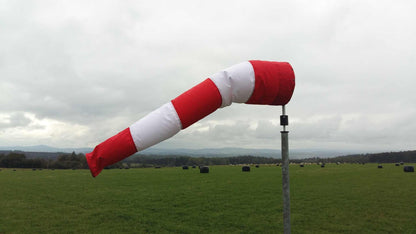 Windsackhülle in Rot-Weiß auf Feld montiert, zeigt Windrichtung; UV-stabilisiert, wasserabweisend.