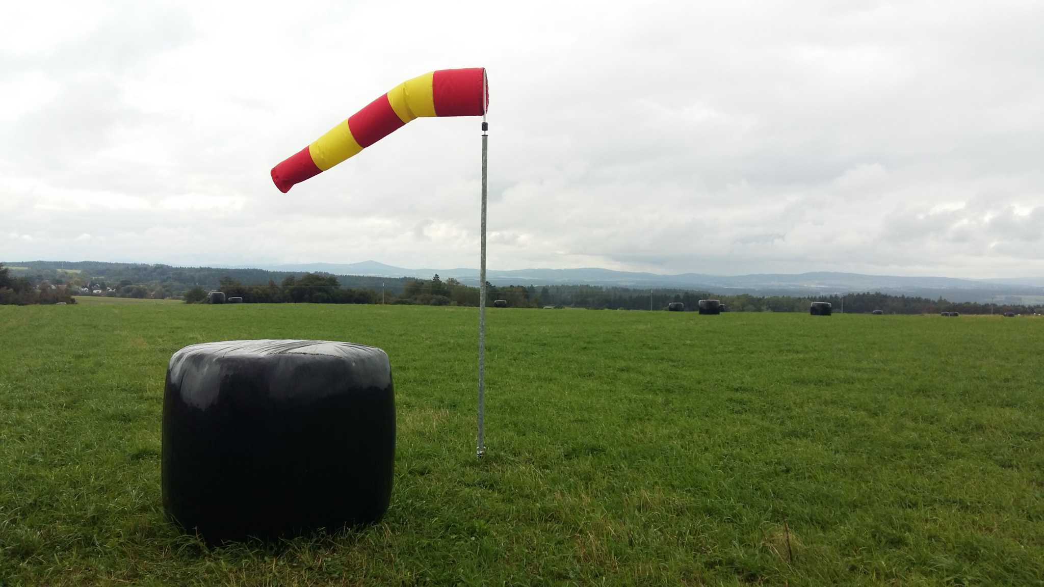 Windsackhülle für Korbdurchmesser 30 cm in Rot/Weiß auf einer Wiese montiert, zur Windrichtungsschätzung.