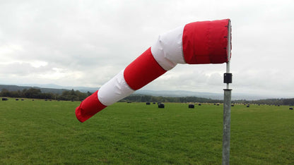 Windsackhülle aus rotem und weißem Polyester, montiert auf einer Stange, zur Schätzung von Windstärke und -richtung.